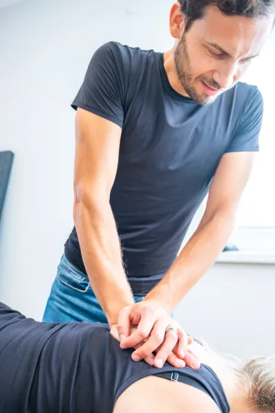 Physiotherapist treating a patient's back with manual therapy.