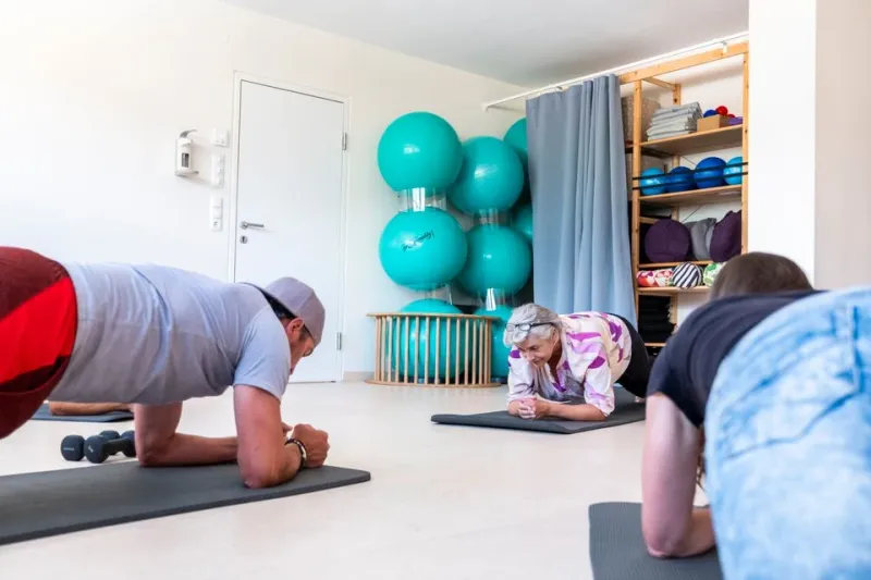 Partecipanti che si allenano insieme in posizione di plank durante un corso al centro terapeutico.