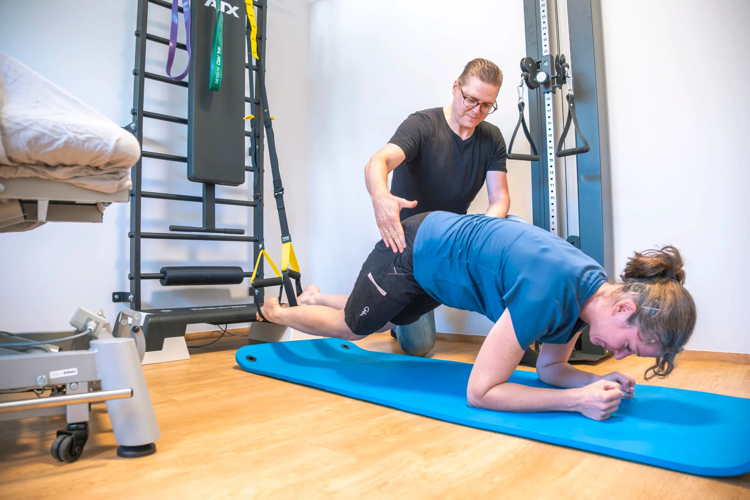 Trainer supporting a man doing a barbell squat in the gym with ATX training equipment.